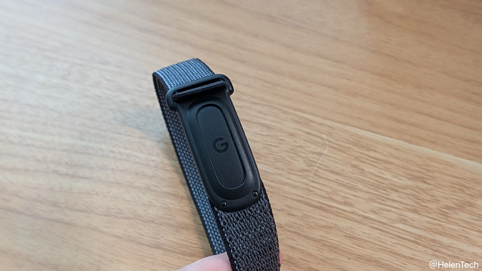 Google Fitbit Air のバンドを持ち上げて本体のロゴ部分にフォーカスしている写真